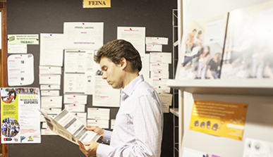 A young man beside a job board reading a job offer 